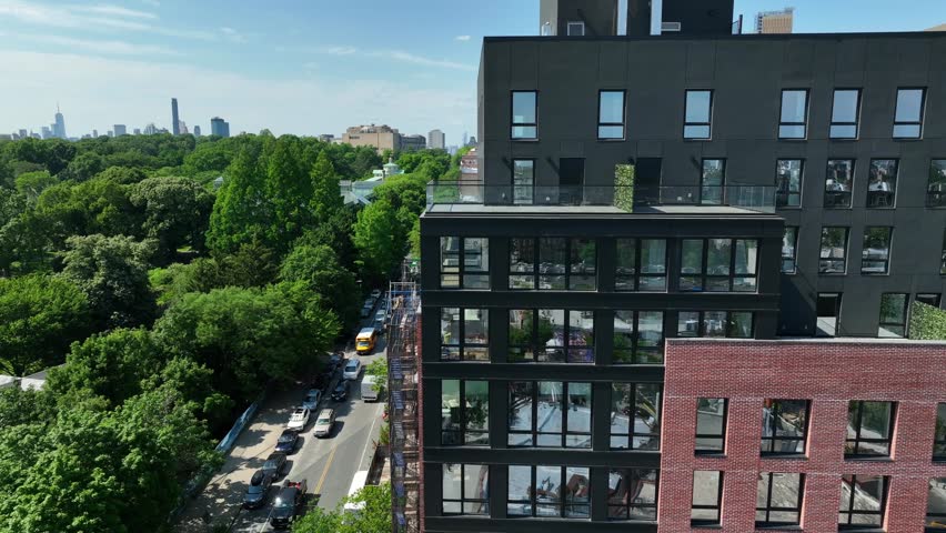 Aerial truck shot of modern apartment building revealing Prospect Park in Brooklyn, New York. Beautiful summer establishing shot in NYC. Royalty-Free Stock Footage #1105577291