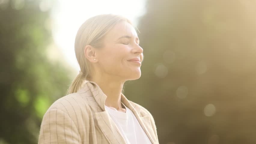 Portrait of confident mature blond woman looking ahead and exhaling fresh air taking deep breath and reducing stress after work at park Successful businesswoman resting for peaceful mind outdoors Royalty-Free Stock Footage #1105578079