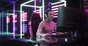 Internet Streamer Making a Live Video Game Broadcast on Social Media Channels. Beautiful Girl Using a Desktop Computer in a Room with Futuristic Neon Background. Gamer Winning and Celebrating
