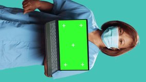 Nurse showing informative video of medical procedure on laptop mock up chroma key green screen. Hospital employee presenting explanatory healthcare tape, isolated over blue studio background