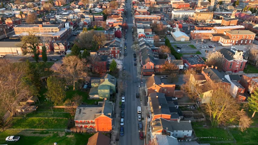 Slow upward tilt view of a large city in the spring, featuring the quietness of small town America. Several city blocks with homes, buildings and annual foliage reflections at sunset.