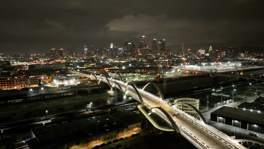 Aerial shot of downtown Los Angeles at night. the 6th street bridge and the LA River can be seen.