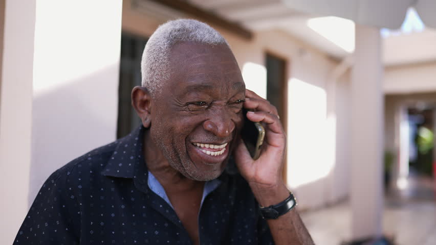 One happy black Brazilian senior man talking on phone outside. Friendly charismatic elderly person using modern technology conversing with smartphone device Royalty-Free Stock Footage #1105588321