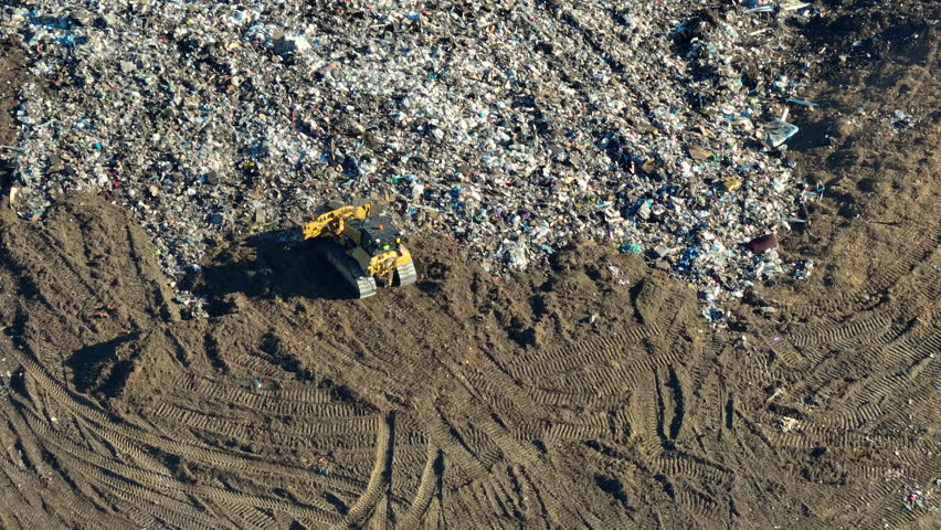 Large landfill site with bulldozer tractors burying trash under ground. Harmful impact of modern consumerism on environment Royalty-Free Stock Footage #1105591493