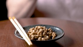 Unrecognizable man adding natto sauce, mixing and eating natto fermented soy beans with chopsticks. Japanese traditional food.
