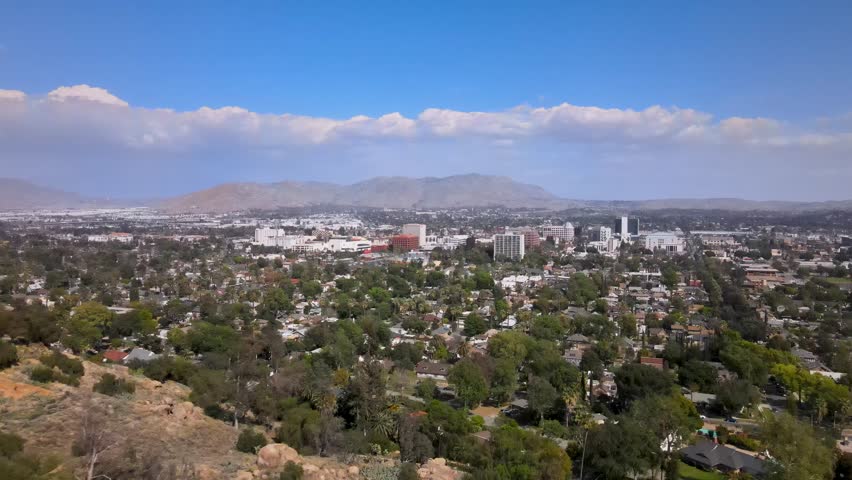 Sun-kissed Riverside, California, under clear skies and striking static clouds, beautifully captured in a forward-moving drone shot