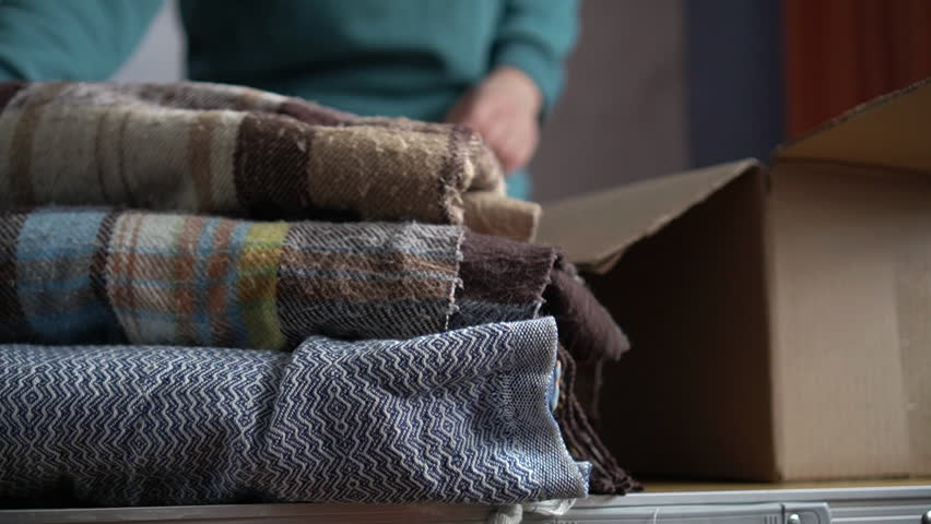 Volunteer stacking warm plaid blankets in a donation box Royalty-Free Stock Footage #1105598435