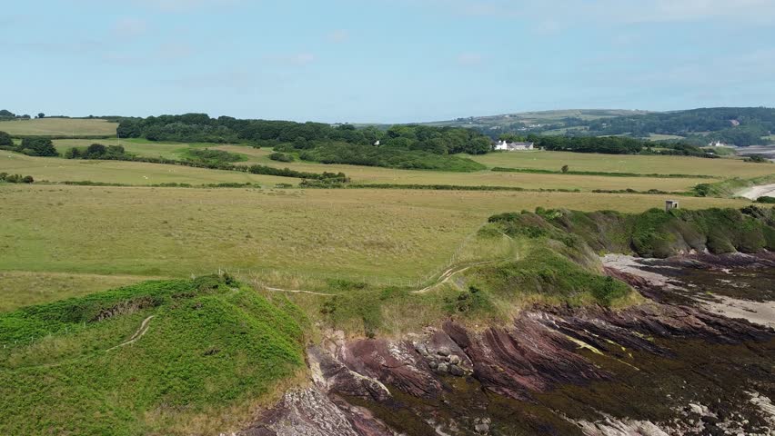 Traeth Lligwy Anglesey eroded coastal shoreline aerial panning view across scenic green rolling Welsh countryside