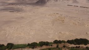 Aerial video of the ancient temple city of Caral. One of the oldest cities of the world. Drone hovers and pans left above the archaeological site. Located in the Supe valley of Lima, Peru.
