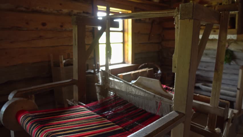 Ancient loom inside an old hut, a knitting and spinning machine. An old manufactory for the production of belts, towels and clothes