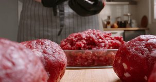The cook prepares meatballs from minced meat using special forms on a wooden table with vegetables and spices Advertising. Minced red meat. Hearty nutritious traditional food