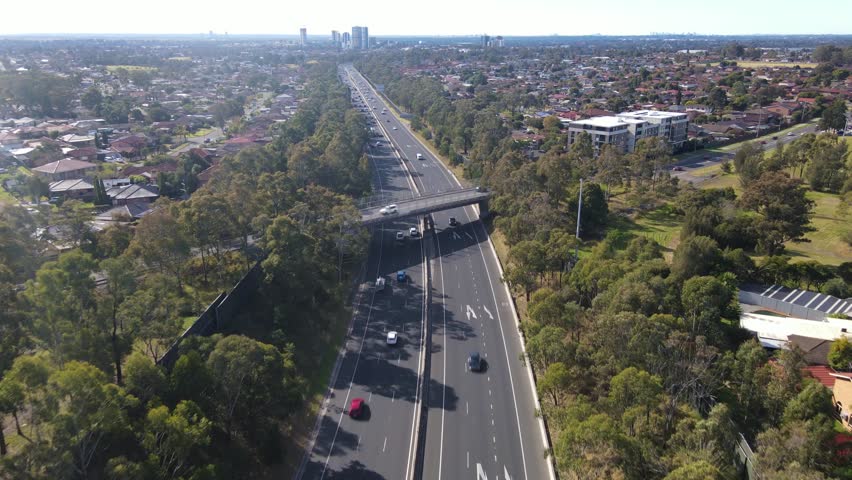 Aerial drone view above the South Western M5 Motorway at Casula in Sydney, NSW Australia with Liverpool CBD in the background  Royalty-Free Stock Footage #1105611155