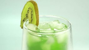 Close up of  kiwi juice on green background. Rotating and dolly video of kiwi. It have juice rich in vitamins and energy. Fresh fruits concept.