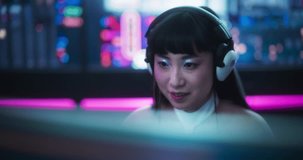 Helpful Japanese Female Having a Conversation on a Video Call, While Sitting Behind a Desk, Using Computer in a Futuristic Technological Office Space. Young Female Manager Working in Tech Support