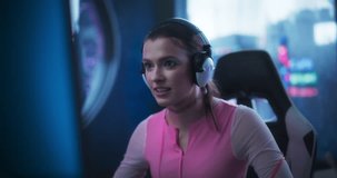 Portrait of a Beautiful Young Female Wearing Headphones, Talking on a Video Call with Friends while Playing Video Games Online on a Computer. Gamer Girl Living in a Futuristic Cyberpunk Apartment
