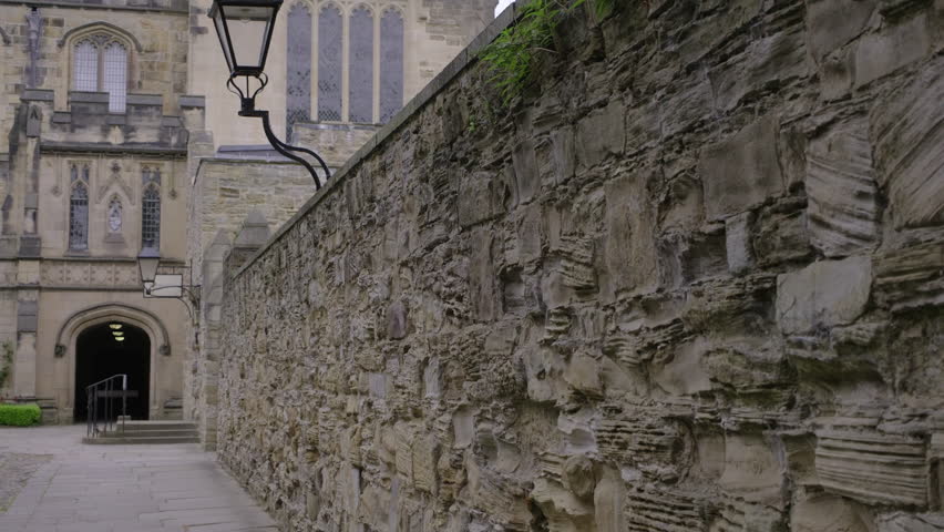 Camera tilts up to reveal the main tower of Durham Cathedral on an overcast spring day