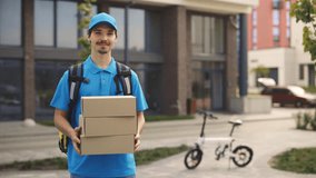 Portrait of the Smiled Positive Caucasian Postman Holding the Paper Boxes. Male Delivery Wearing Special Uniform Showing the Boxex to the Camera. People and Professions. Delivering Service - Powered by Shutterstock - Get 15% off with code: PIKWIZARD15