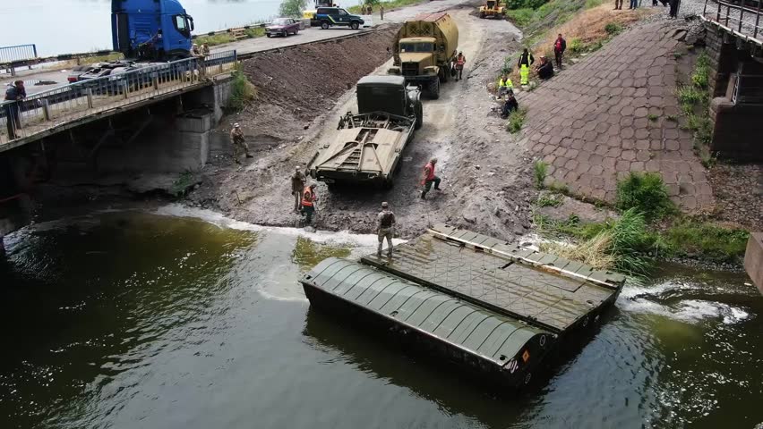 Pontoon bridge of the Ukrainian army. Installation of a temporary crossing near the destroyed bridge. Soldiers collect pontoon ferry. Top view from a drone. 