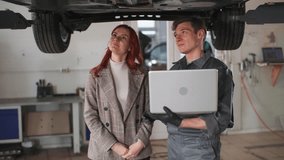 car service, male auto mechanic with laptop in hands shows female client machine diagnostics while standing on hydraulic ramp - Powered by Shutterstock - Get 15% off with code: PIKWIZARD15