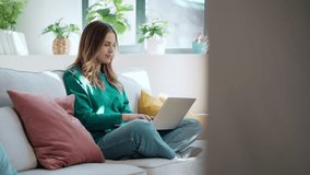 Video of beautiful kind woman working with laptop while sitting on couch in living room at home - Powered by Shutterstock - Get 15% off with code: PIKWIZARD15