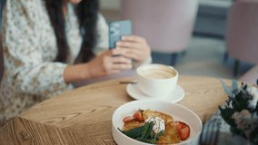 Young Asian woman blogger filming food in a restaurant on a smartphone