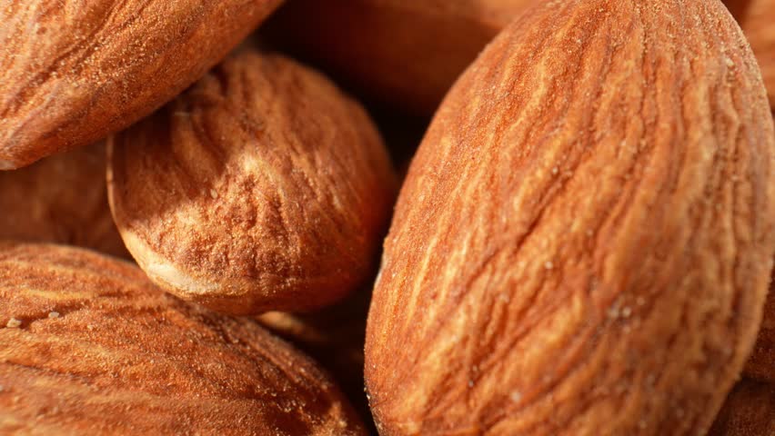 In a macro video of almond kernels, the intricate details and textures of the almonds are captured in stunning close-up shots. Food and snack concepts. Almond kernels background. 4K HDR
