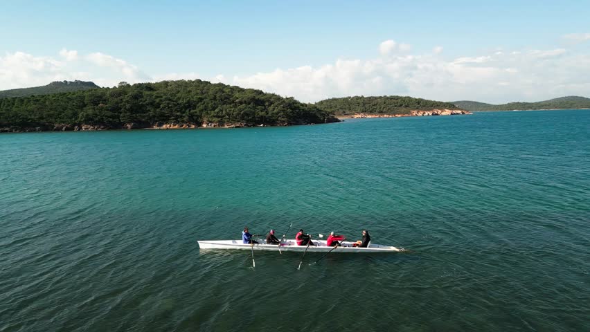 Sport Canoe with a team of four people rowing on tranquil water, Aerial view.
