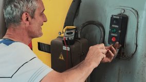 A professional electrician repairs industrial equipment in a production workshop. Diagnostics of the power supply of the starting mechanism of the unit. Authentic video of the workflow.