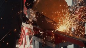 Worker cuts metal channel with circular saw in production room and sparks fly. Video of authentic workflow.