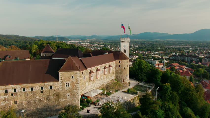 Aerial view of Ljubljana Castle in capital of Slovenia, Central Europe, EU. Medieval Fortress with flags on green Hill in old downtown as a key landmark. Sightseeing and travel. 4k drone orbit shot Royalty-Free Stock Footage #1105633425