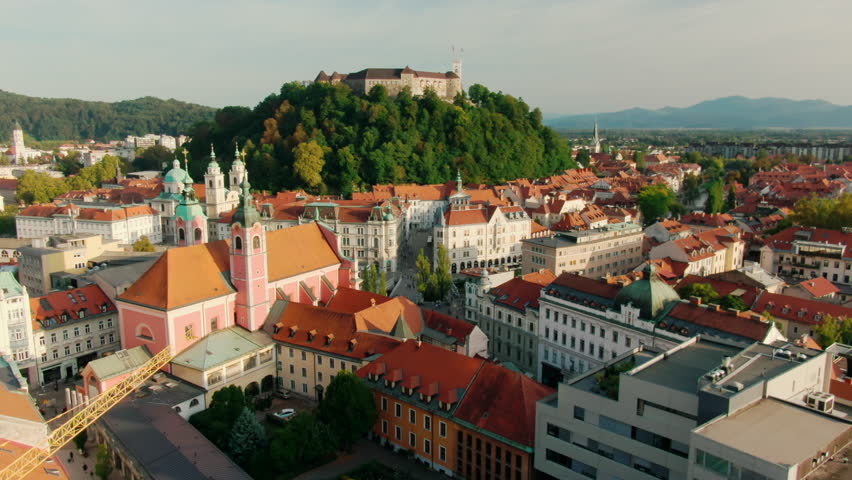 Establishing Aerial view of Ljubljana Castle on hill in historical city. Capital of Slovenia, Central Europe. Ancient chateau with Slovenian flags and buildings of old town. 4k drone zoom in shot Royalty-Free Stock Footage #1105633429