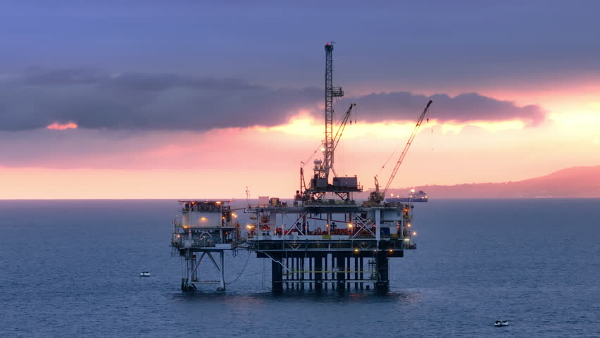 Aerial view of illuminated oil well structure with distant misty view of island and vessels with incredible beauty of the sky. Dawn in San Pedro Channel. High quality 4k footage Royalty-Free Stock Footage #1105635579