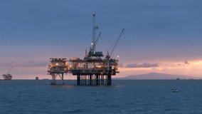 Large illuminated oil drilling rig with several ships on the background. USA. Offshore facility for extraction of oil and gas in San Pedro Channel at dawn. High quality 4k footage