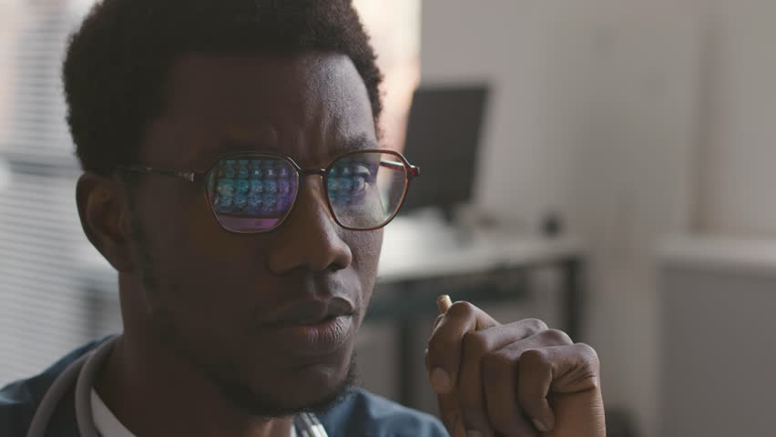 Medium closeup of young Black male neurologist analyzing MRI of patient reflecting in his eyeglasses Royalty-Free Stock Footage #1105638237