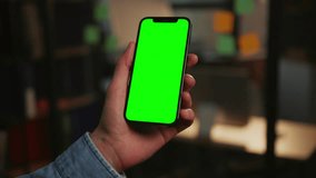 Footage of person holding phone with simulated green screen. Man using smartphone in vertical position isolated on blurred background. Cellphone. Communication concept. Office - Powered by Shutterstock - Get 15% off with code: PIKWIZARD15