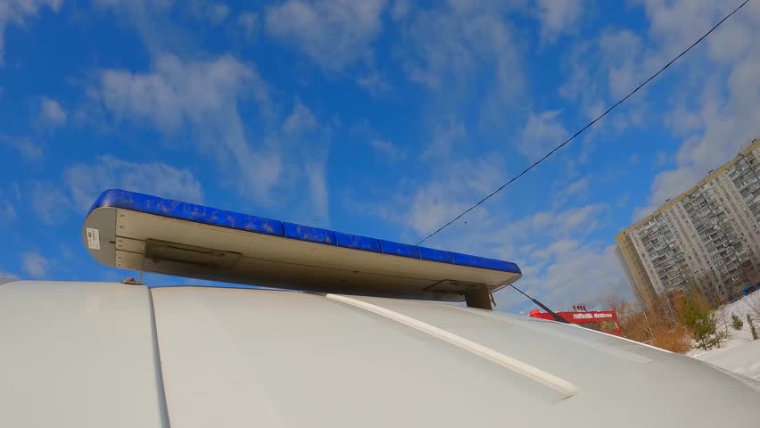 ambulance car moving fast on city street, closeup view of blue lights on roof against sky