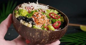 Person showing a poke bowl with salmon, broccoli and edamame beans, bowl with fresh vegetables and raw fish, trendy food, close up detailed video, 4k footage