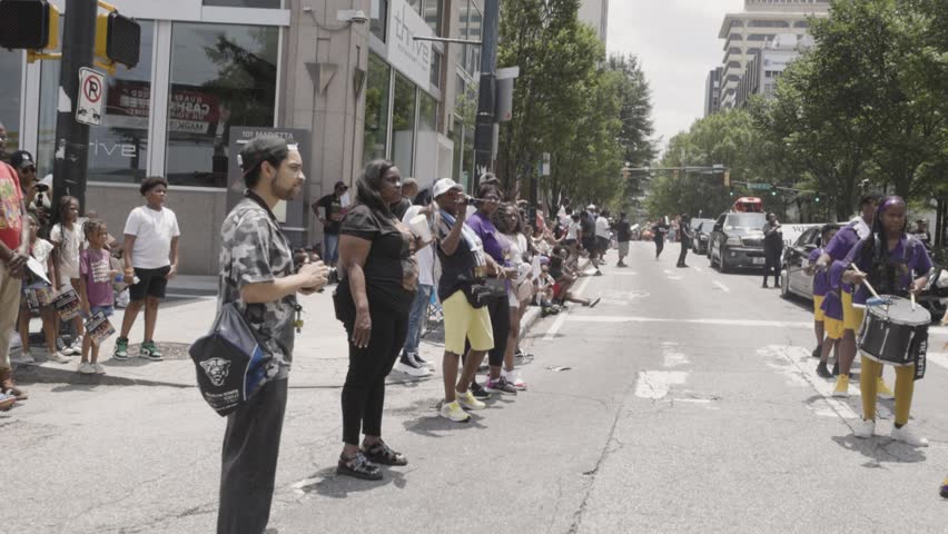 Atlanta, GA  USA – June 17, 2023:  Handheld shot moves along large crowd of spectators lined up on Marietta Street, watching the Juneteenth parade on June 17, 2023 in Atlanta, GA. 