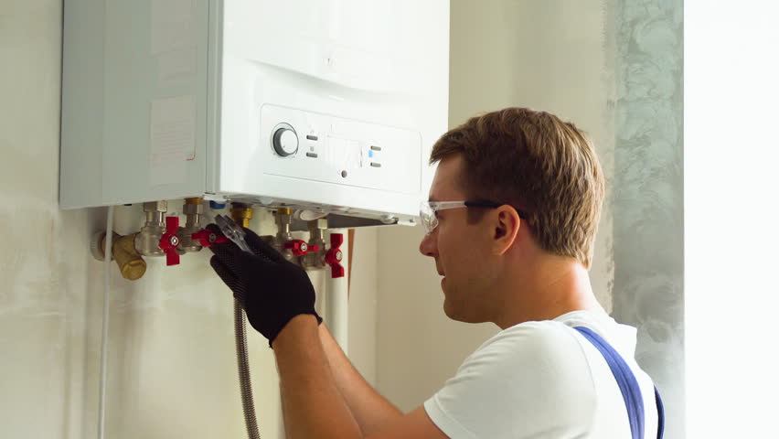 Serious technician setting the new gas boiler for hot water and heating