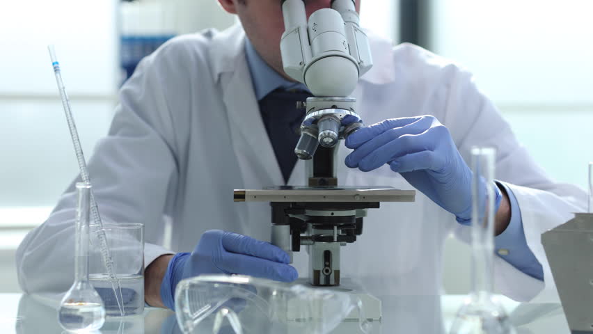 close up. the scientist looks through the microscope