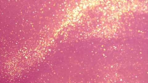 Abstract background of moving gold particles in pink fluid. Magic Gold sparkling glitter smooth motion. Gold dust particles moving chaotically and flowing in pink liquid. Arkistovideo