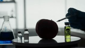 Dark silhouette of a male scientist with a syringe in his hand. A researcher injects pesticides and nitrates into a red apple with a syringe. GMO concept and genetically modified organism. - Powered by Shutterstock - Get 15% off with code: PIKWIZARD15