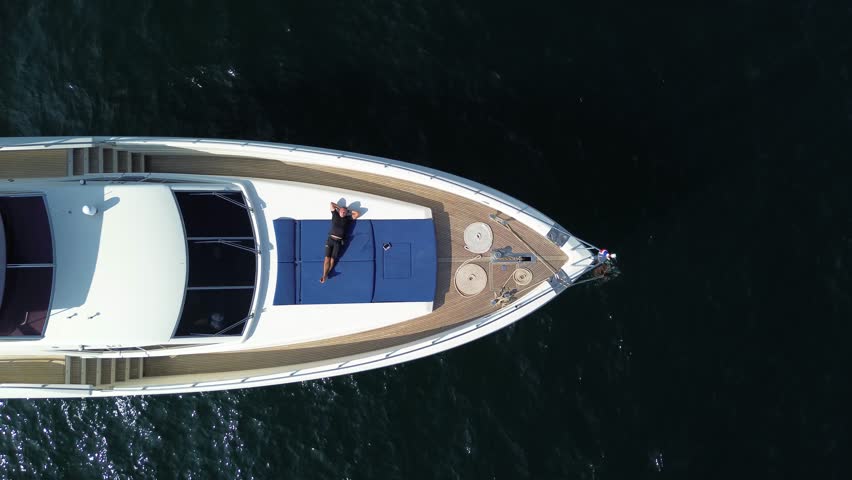 Young businessman relaxing on a luxury private yacht, top down view of a man on a yacht