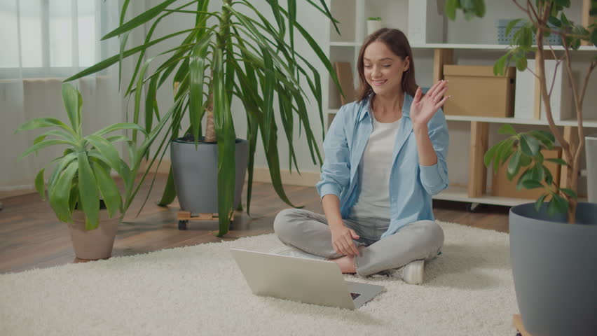 Smiling Young Woman Sitting at Laptop on the Floor Among Flowers. Plants Improve Mood and Well-being, Woman Works at Home, Studying at Home, Woman Talking Online, Woman Making Video Call Royalty-Free Stock Footage #1105677073