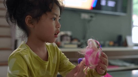 Little girl playing with doll while speaking to her mum. วิดีโอสต็อก