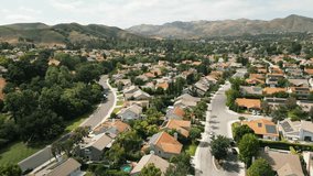 Aerial view of typical suburban area in Los Angeles, Califonia, USA. Wealthy villas with swimming pools. Hills and mountains. Drone flyover of residential houses in sunny day. High quality 4k footage
