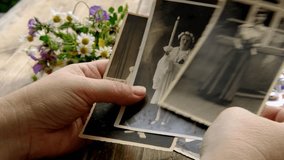 female hands holding paper envelope with old photographs, bouquet of wild flowers on table wooden table in garden, blurred natural background, concept of genealogy, memory of ancestors, family tree - Powered by Shutterstock - Get 15% off with code: PIKWIZARD15