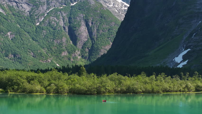 Scenic Glacial Lake Canoeing. Caucasian Sportsman in the Kayak on the Turquoise Water. Panoramic Photo.