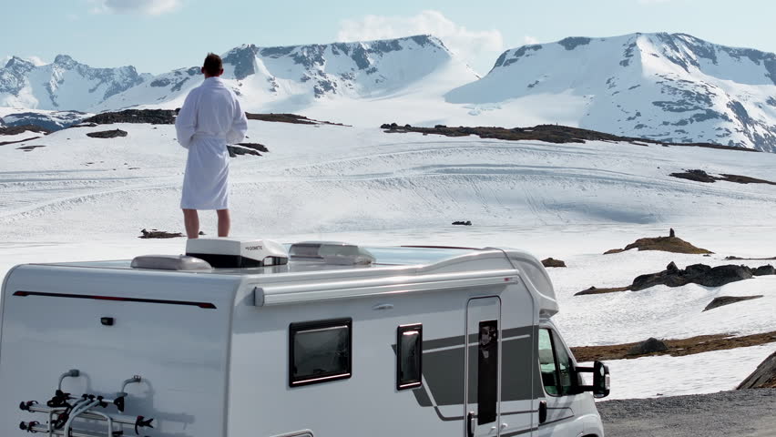 Funny Caucasian Tourist Enjoying Breathtaking Snowy Norwegian Landscape Fron His Camper Van Roof