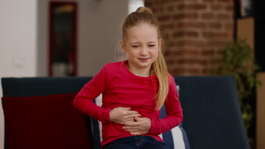Kids and healthcare concept. Upset little girl suffering from stomach pain at home, massaging her belly and grimacing, tracking shot, free space Royalty-Free Stock Footage #1105692845